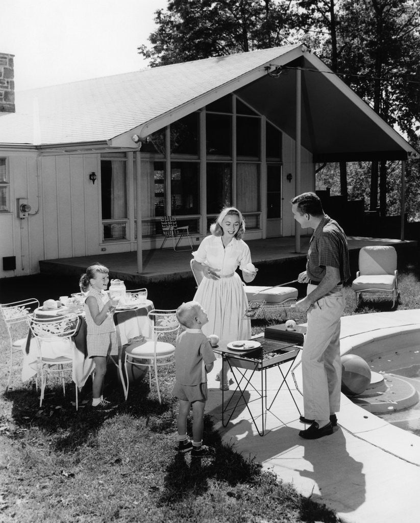 Detail of 1950s family grilling hamburgers beside pool in backyard cookout by Anonymous