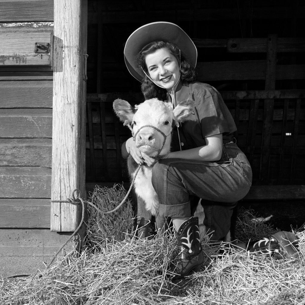 Detail of Girl posing with calf in straw filled stall in barn by Anonymous