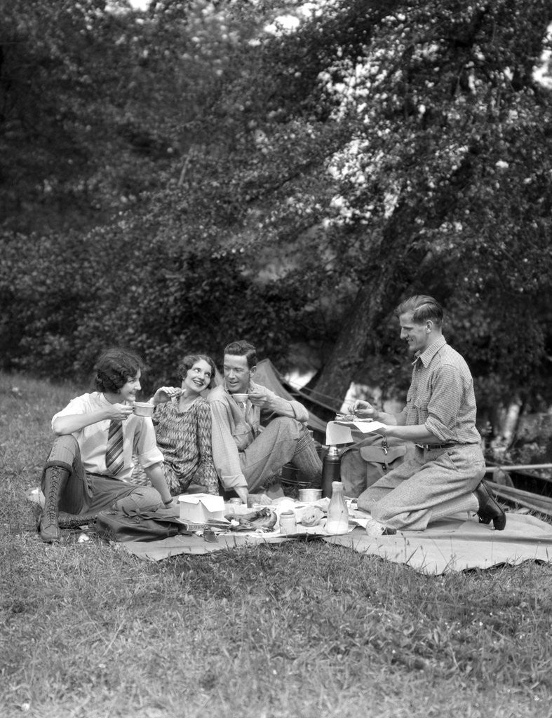 Detail of 1920s four people two couples men women sitting on ground enjoying a picnic by Anonymous