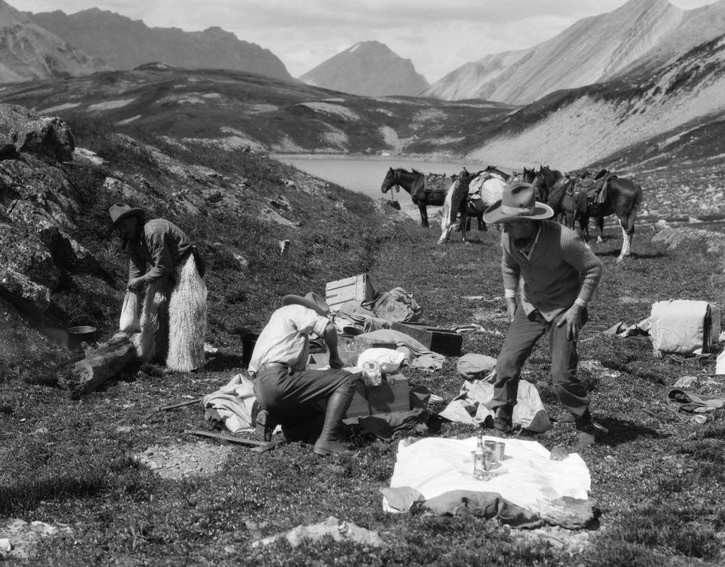 Detail of 1920s 1930s three men cowboys at campsite preparing food horses in background alberta canada by Anonymous
