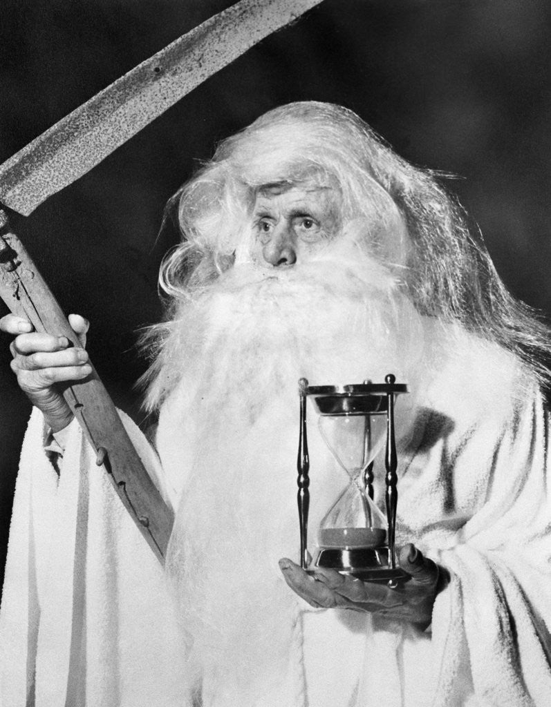 Detail of 1950s costume elderly man long beard angel of death sickle scythe hourglass father time by Corbis