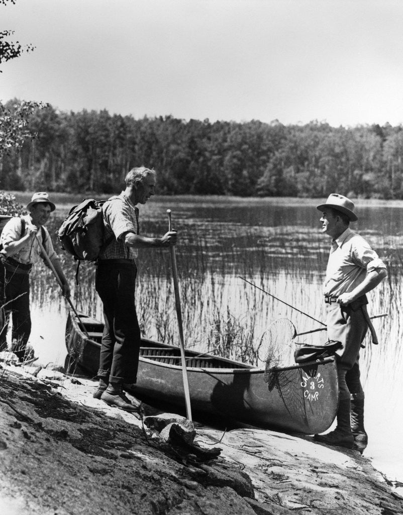 Detail of 1930s three fishermen standing beside canoe holding fishing gear net backpack lake of the woods ontario by Anonymous