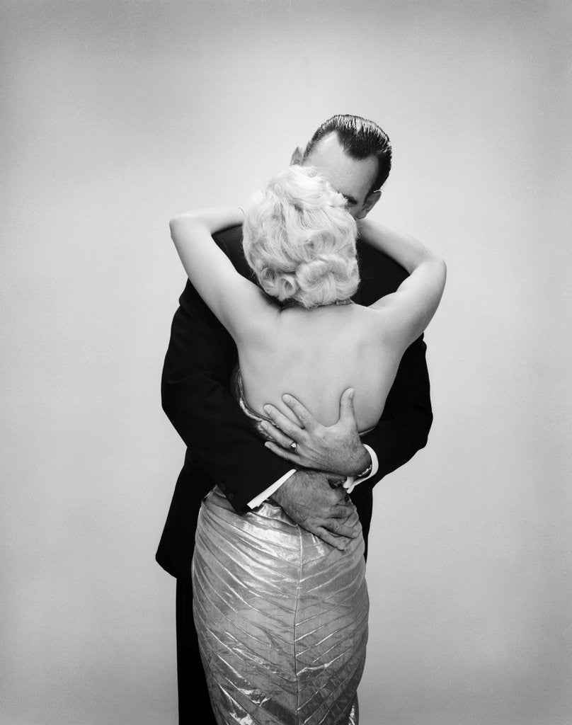 Detail of 1950s 1960s kissing couple blond woman backless satin evening dress man embracing from behind by Corbis