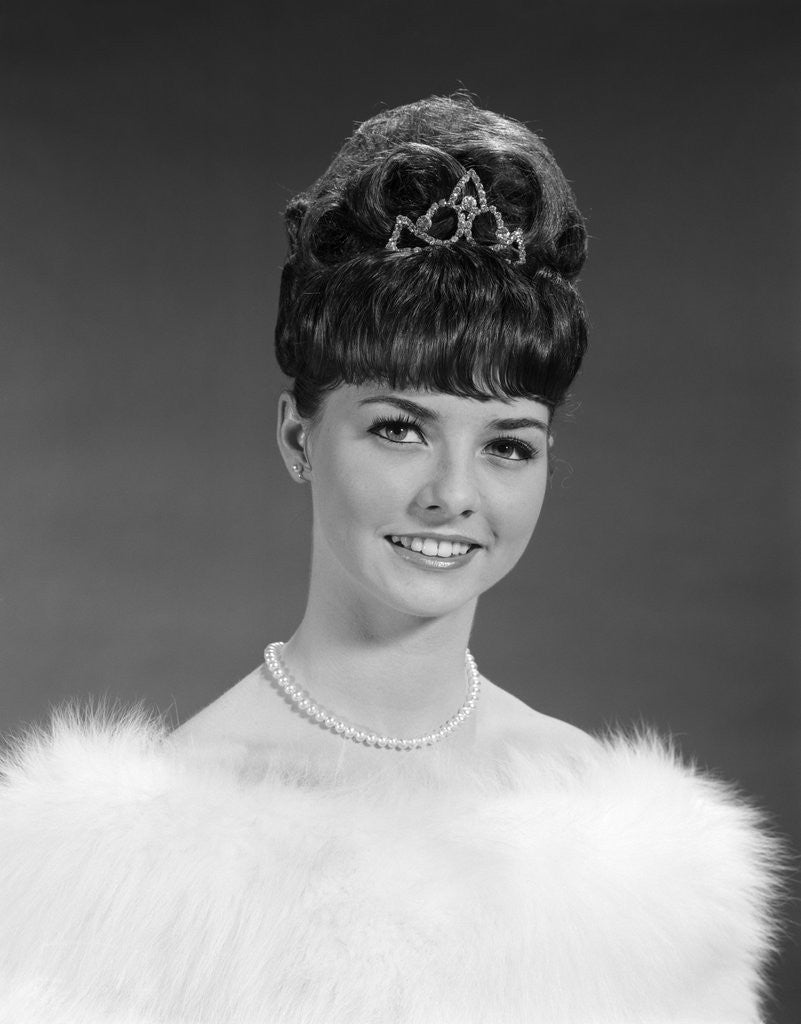 Detail of 1960s pretty young woman wearing tiara fur stole and string of pearls looking at camera by Anonymous