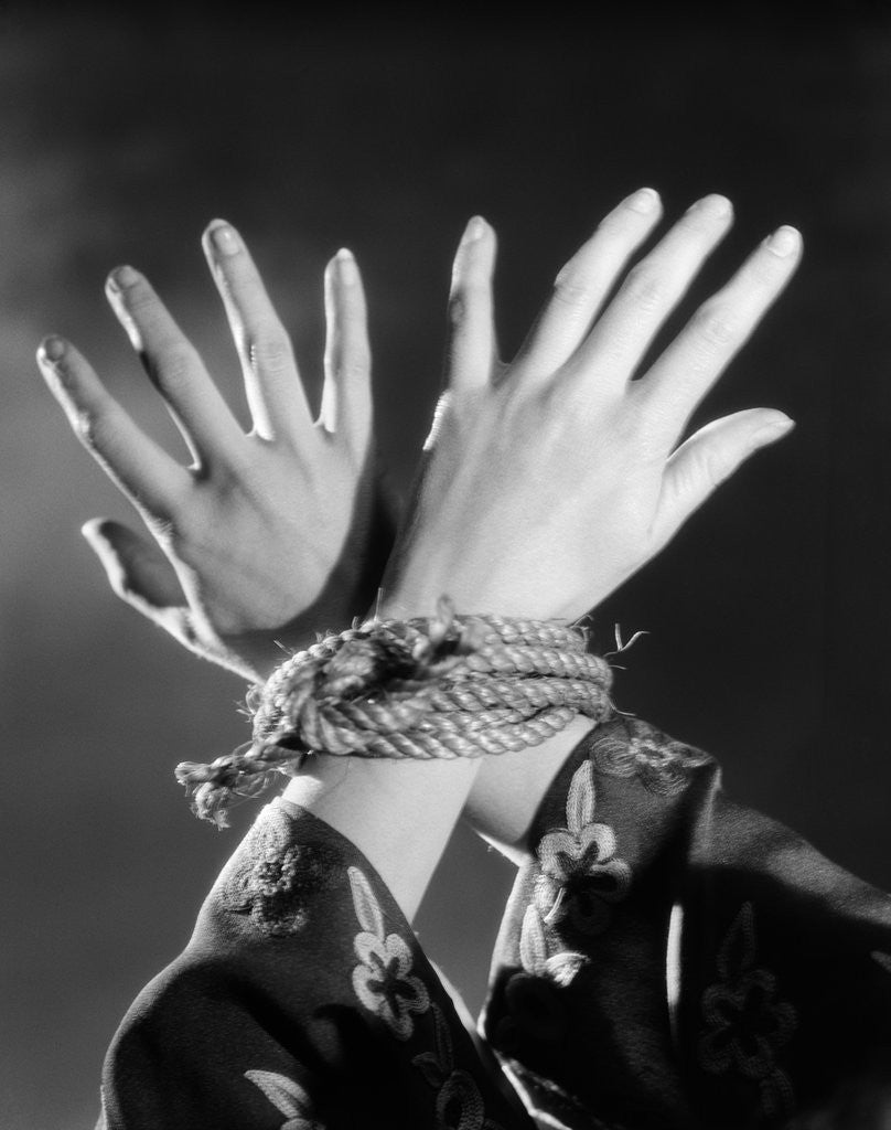 Detail of 1930s woman's hands tied together by rope overhead view by Anonymous