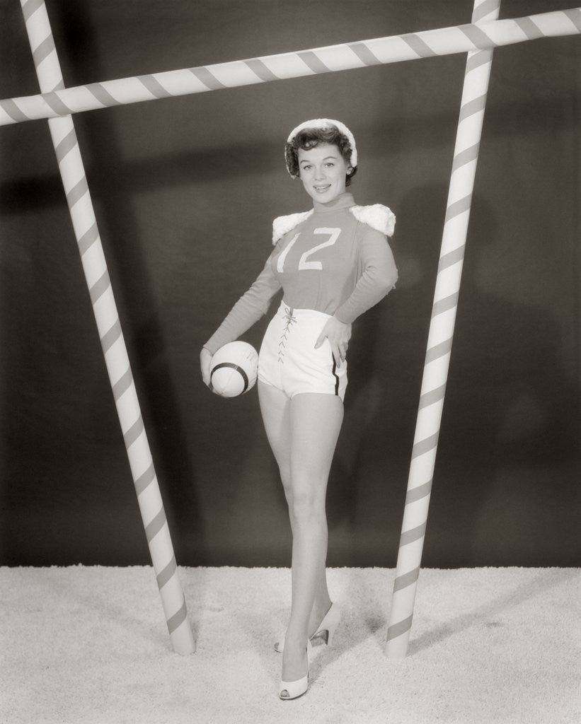 Detail of 1950s 1960s woman in sexy football costume at goalpost by Corbis
