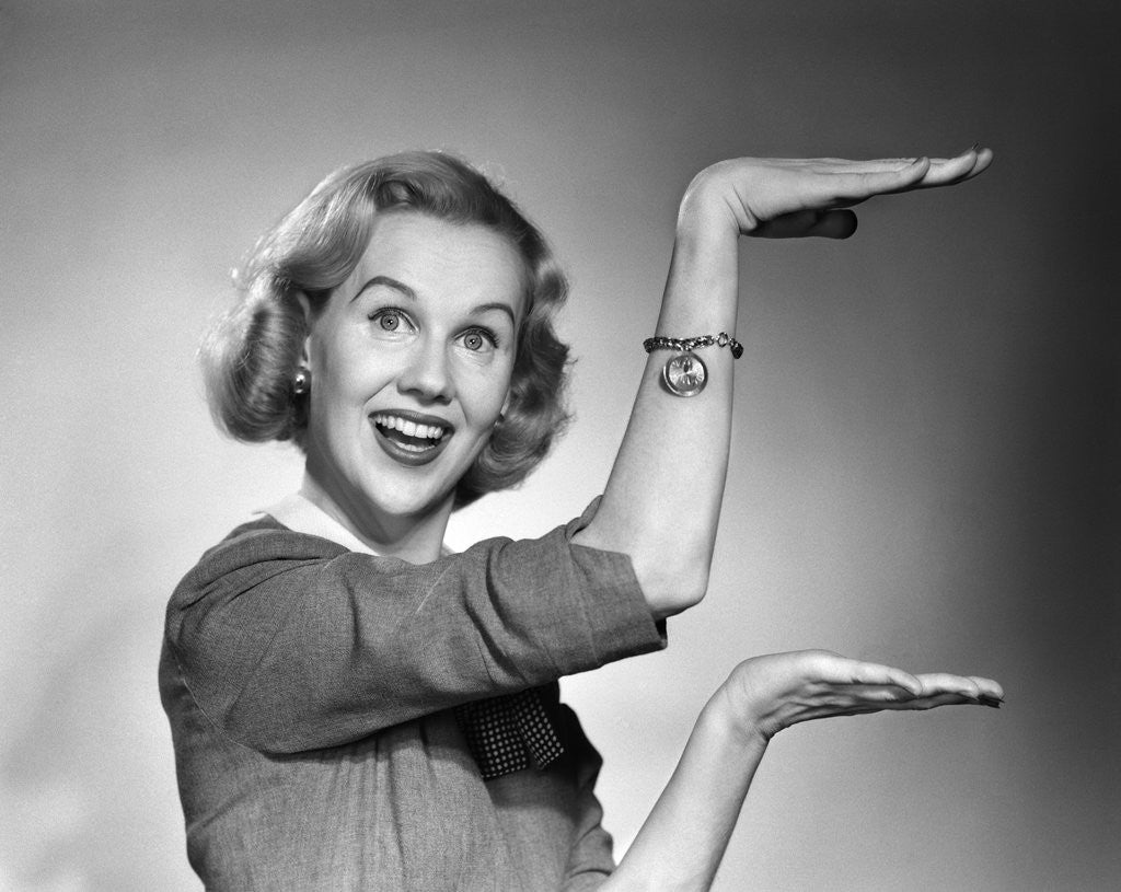 Detail of 1950s 1960s happy smiling blond woman gesturing with hands showing size of something looking at camera by Corbis