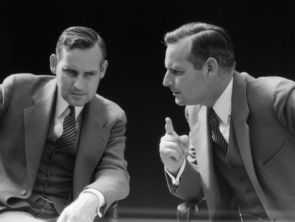 Detail of 1930s 1940s businessman talking seriously to himself or his twin alter ego by Corbis