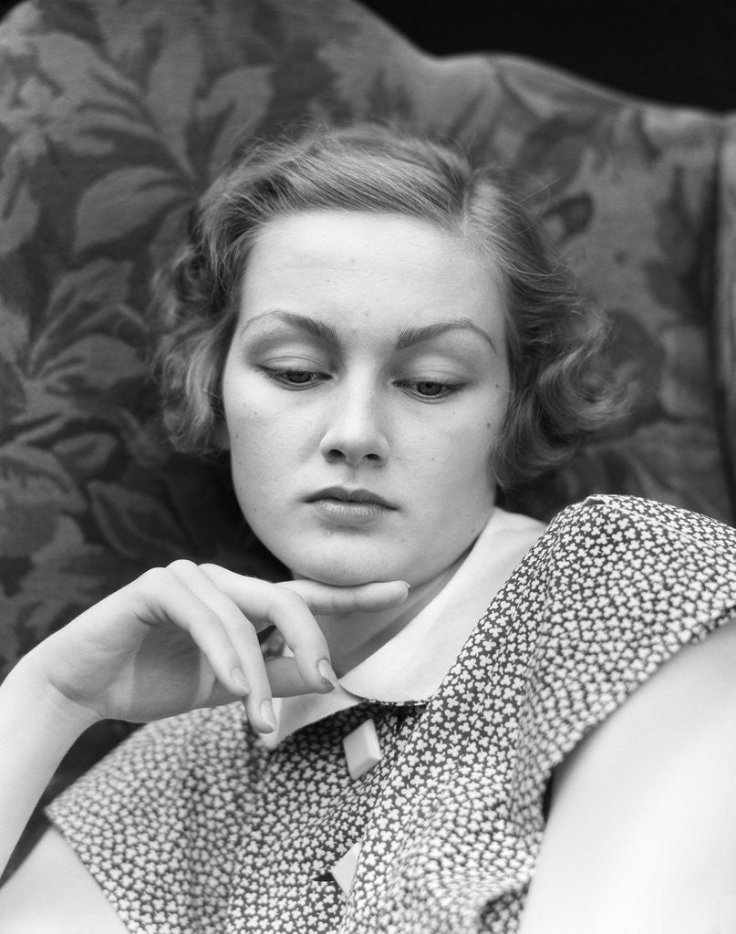 Detail of 1930s portrait of woman looking down with sad expression and her chin resting on index finger by Anonymous