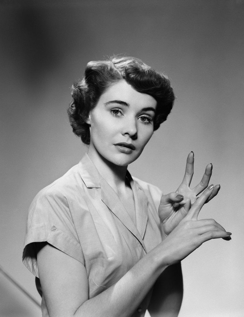 1950s serious woman counting on hands by Corbis