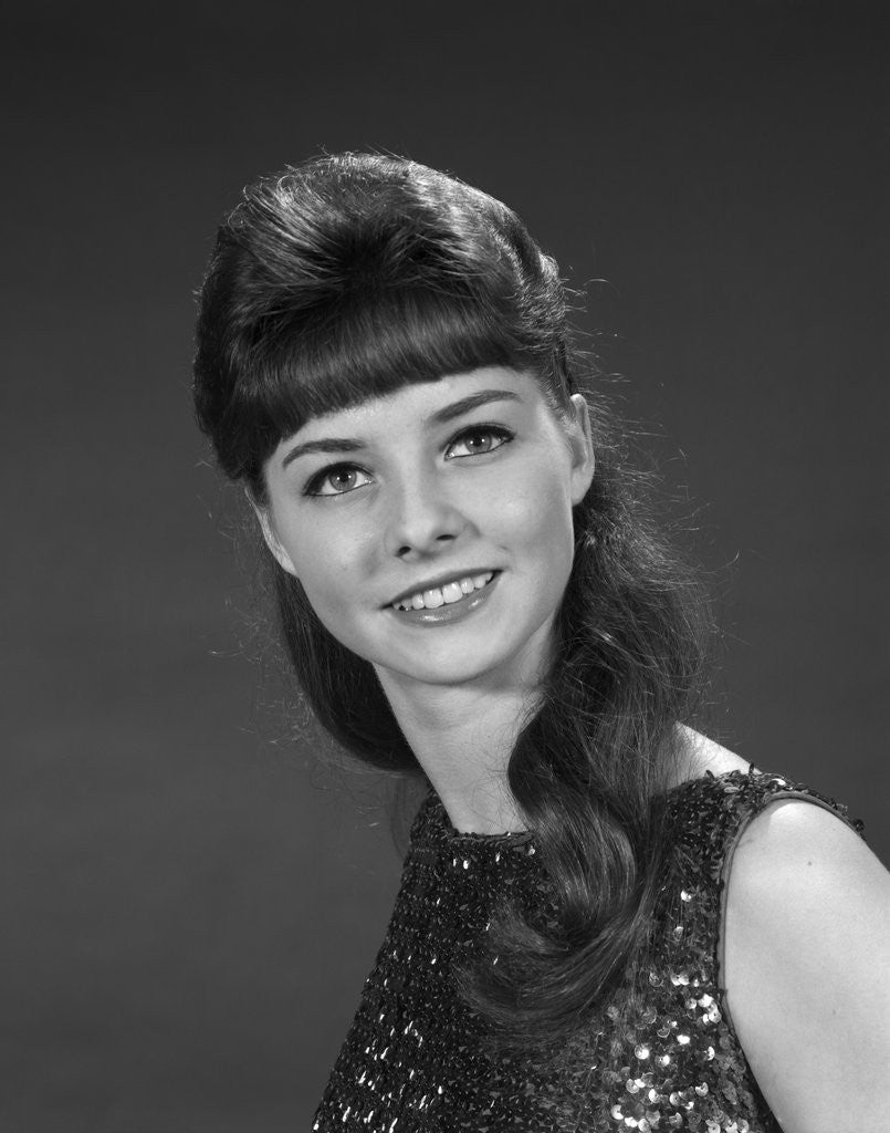 Detail of 1960s portrait of smiling young woman in sequin dress looking at camera by Anonymous