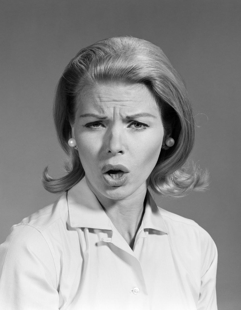 Detail of 1960s woman blond hair in flip looking at camera mouth open angry mad facial expression by Corbis