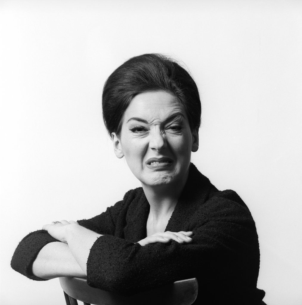 Detail of 1960s 1970s brunette middle aged woman making funny face looking at camera with wrinkled nose and arms folded on back of chair by Anonymous