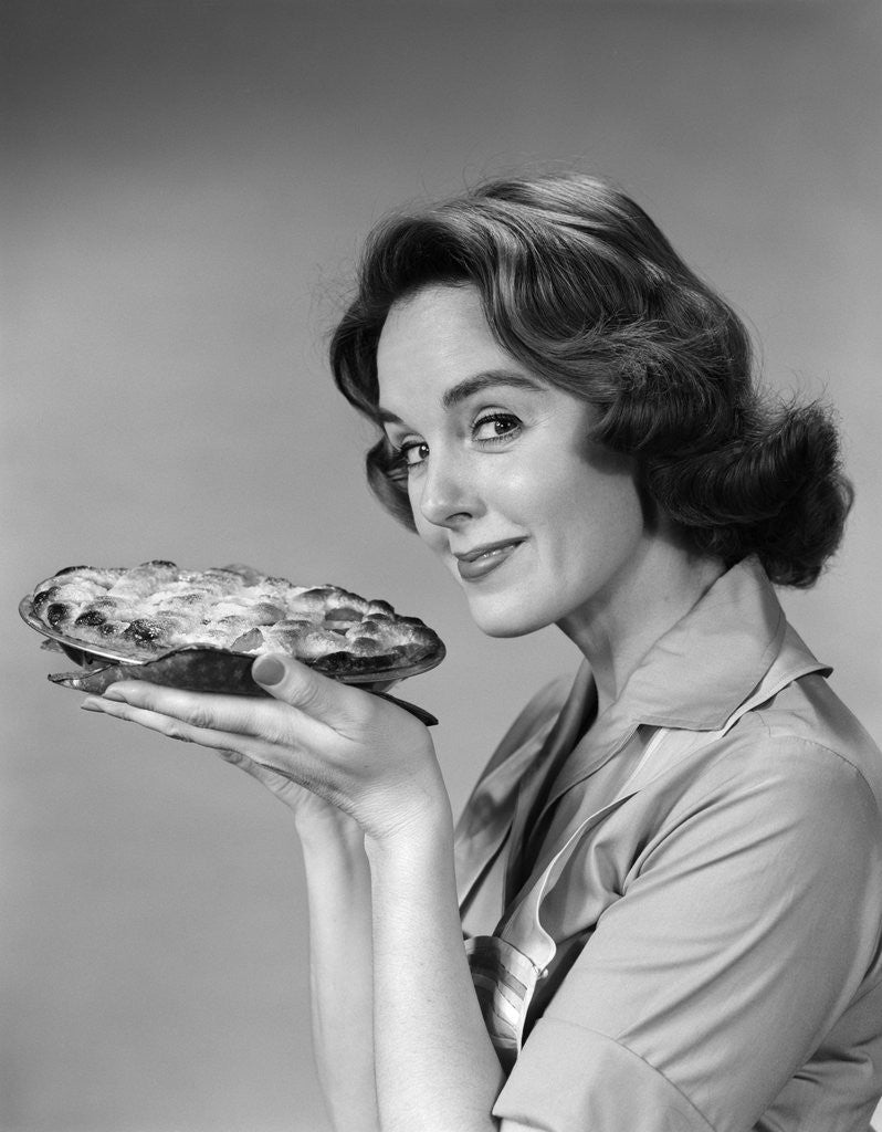 Detail of 1950s 1960s woman smiling holding freshly baked pie looking at camera by Corbis