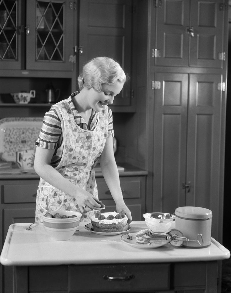 Detail of 1930s woman in kitchen making strawberry shortcake by Anonymous