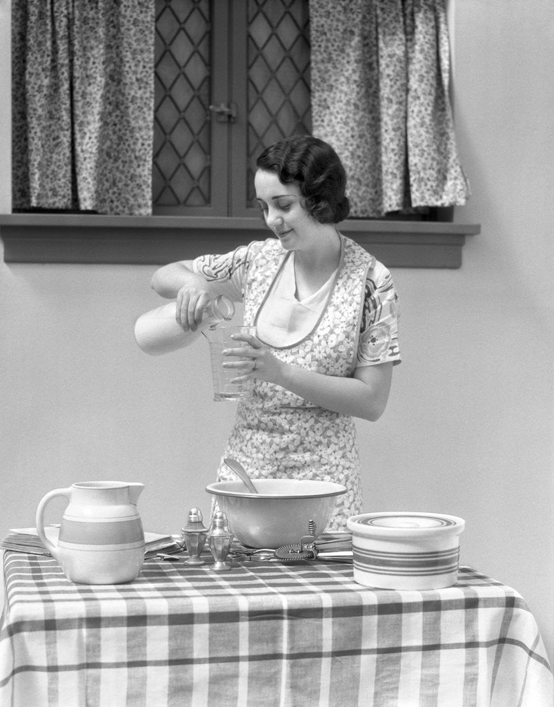 Detail of 1920s 1930s woman pouring milk into measuring cup by Corbis