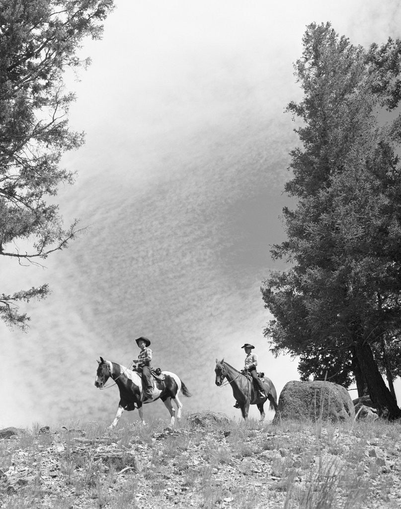 Detail of 1950s 1960s two men on horseback riding across field wearing cowboy hats by Anonymous