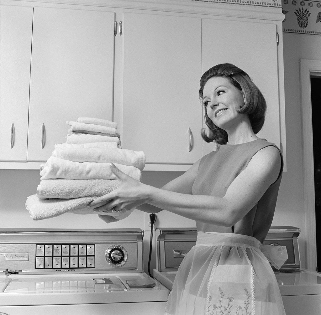 Detail of 1960s satisfied woman homemaker holding folded laundry by Anonymous