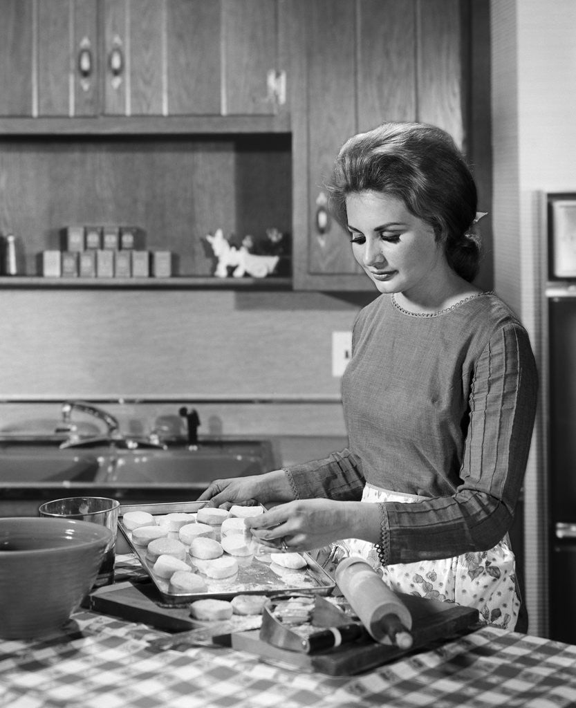 Detail of 1960s woman housewife baking biscuits in kitchen by Anonymous