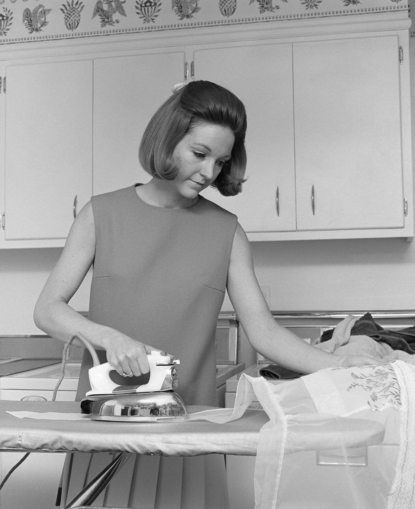 Detail of 1970s woman ironing an apron with steam iron by Corbis