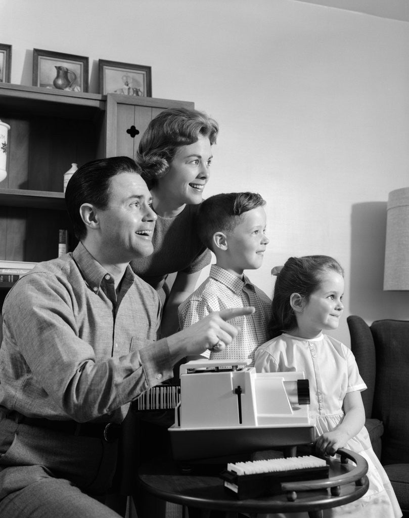 Detail of 1960s happy family looking at slides on slide projector by Corbis