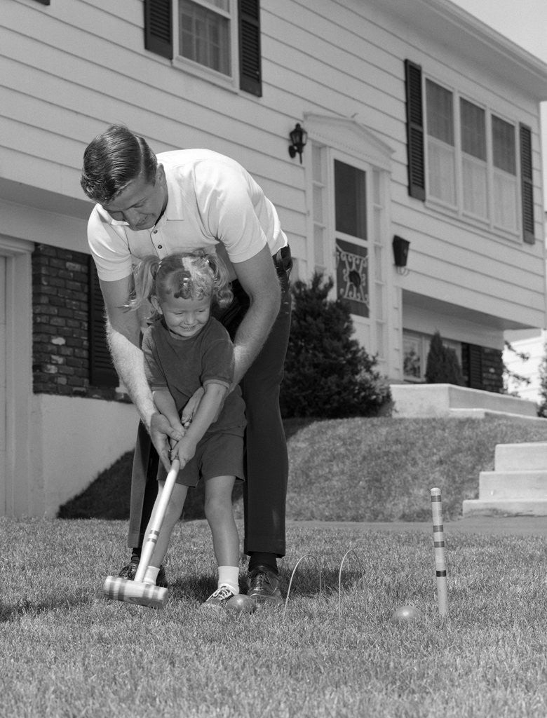Detail of 1960s father and young daughter playing croquet in yard by Anonymous