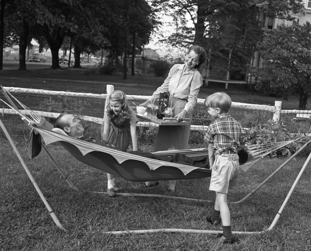 Detail of 1950s mom & kids serving dad in hammock by Anonymous