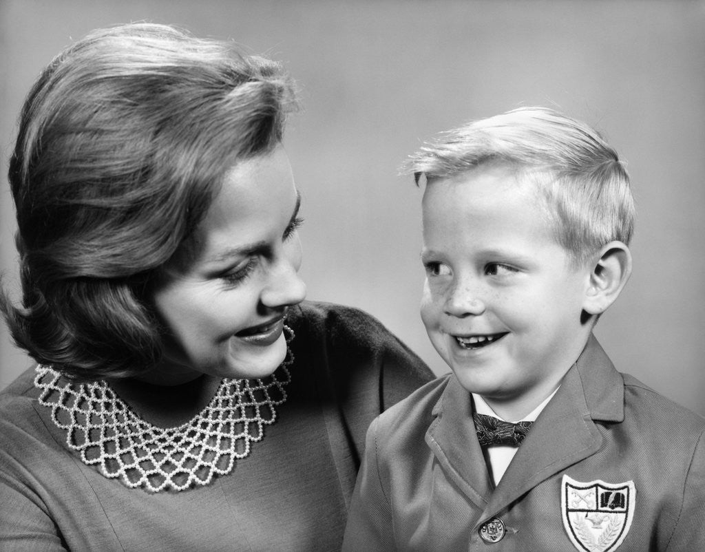 Detail of 1960s portrait mother with arm around son dressed in school uniform with bow tie & emblem crest on jacket mom pearl lace collar by Anonymous