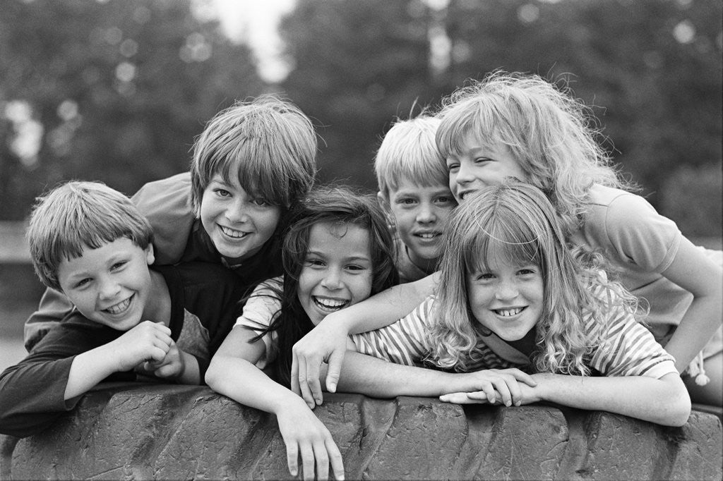 Detail of 1970s 1980s group of six boys & girls gathered together on large playground tire by Anonymous