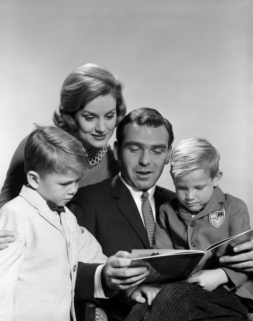 Detail of 1960s family father mother sons reading book together by Anonymous
