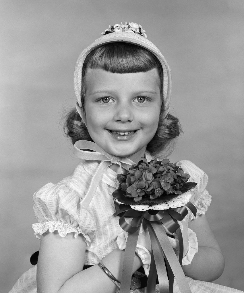 Detail of 1950s child holding flowers smiling looking at camera by Anonymous