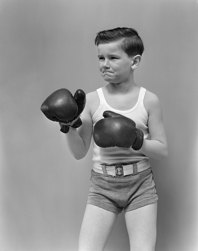 Detail of 1940s boy child wearing boxing gloves standing ready to fight by Anonymous