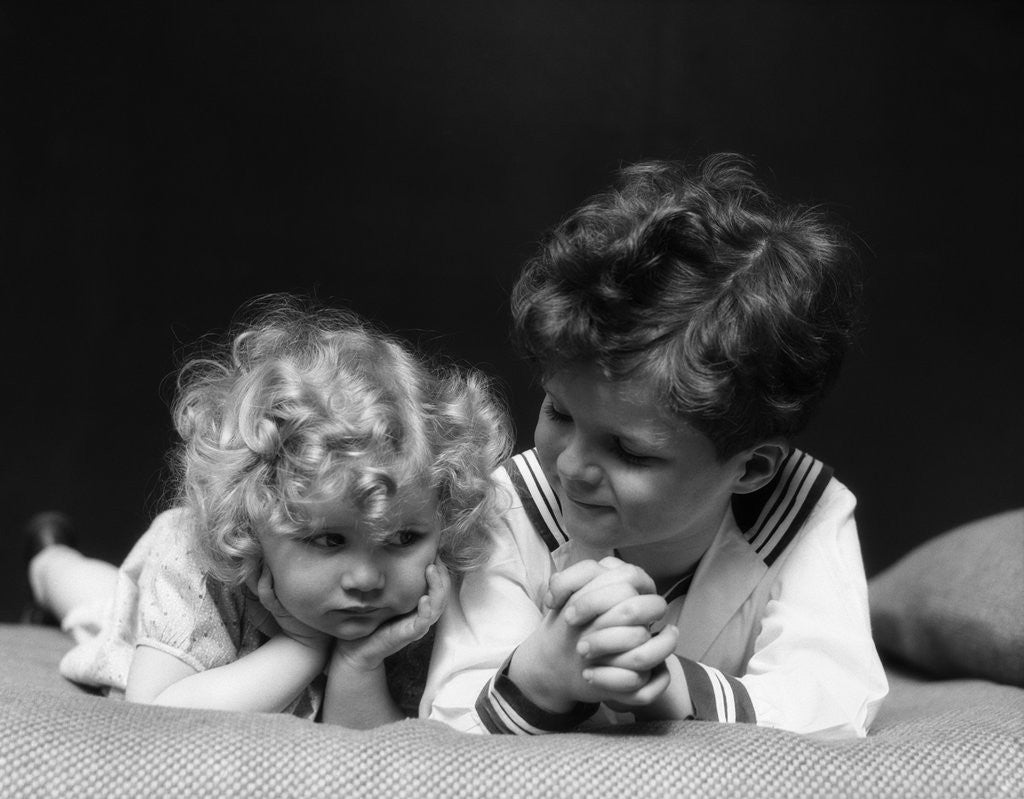 Detail of 1930s two children brother and sister lying on couch by Anonymous