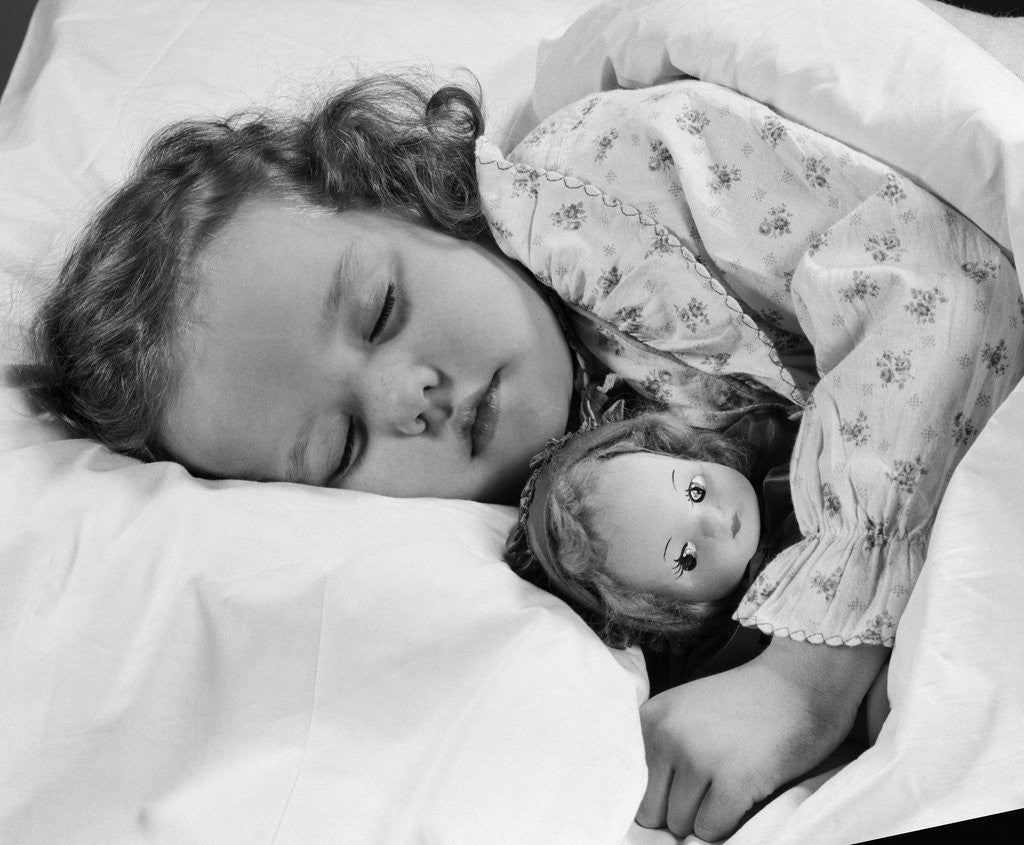 Detail of 1950s child little girl sleeping in bed with doll by Anonymous
