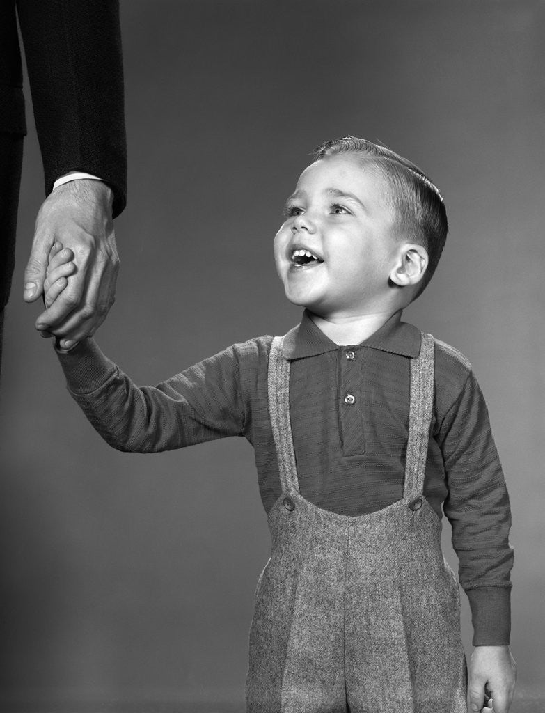 Detail of 1960s boy holding adult male hand smiling by Anonymous