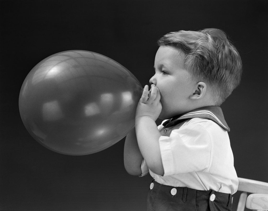 Detail of 1940s boy blowing up balloon by Corbis