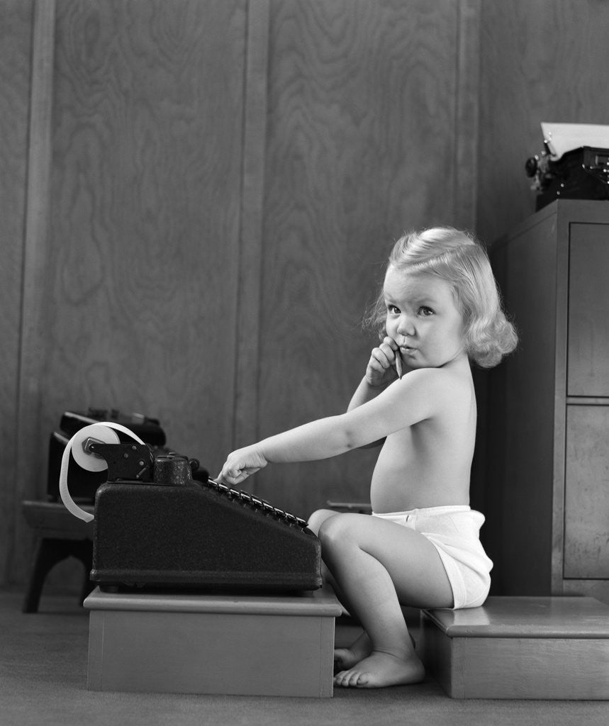 Detail of 1940s child sitting typing on adding machine funny facial expression by Corbis
