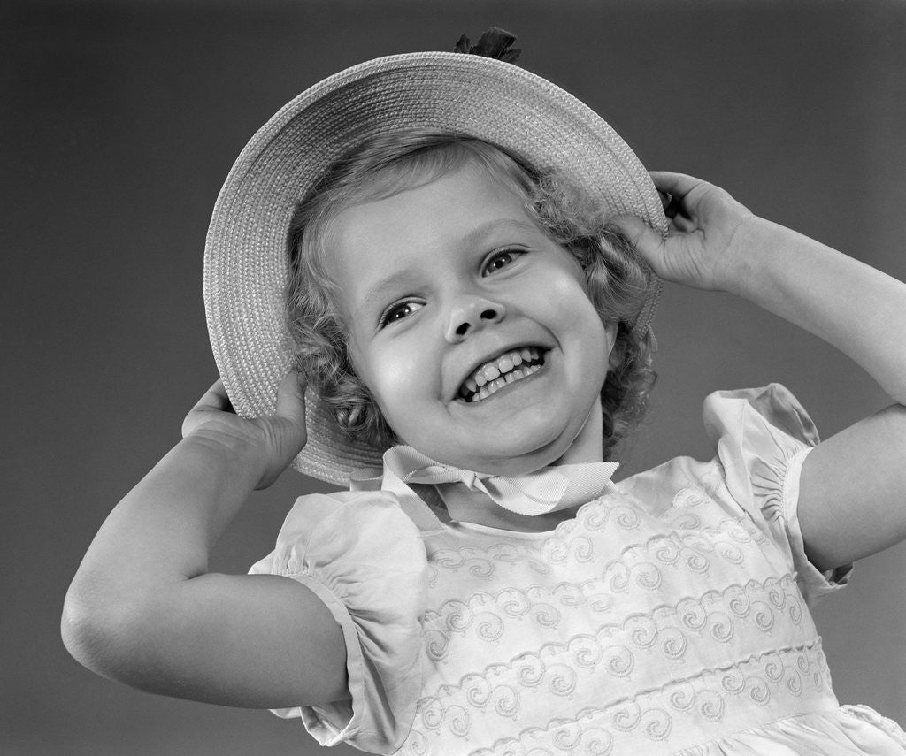 1950s child smiling little girl wearing pretty dress and straw hat by Corbis