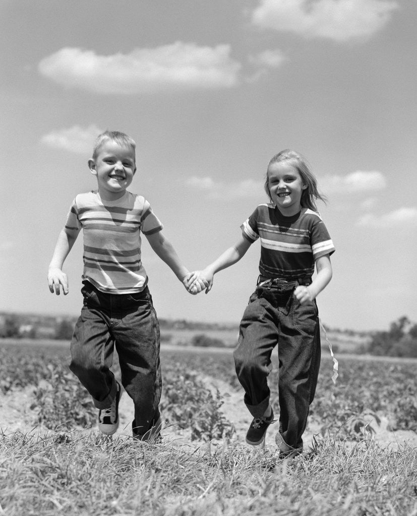 Detail of 1950s boy girl running grassy farm field holding hands by Anonymous