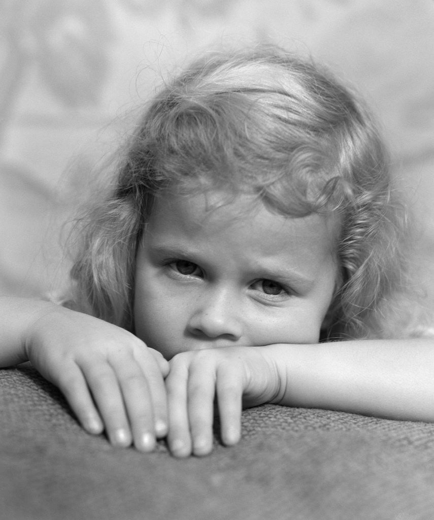 Detail of 1930s portrait sad little blond girl peeking over her hands looking at camera by Anonymous