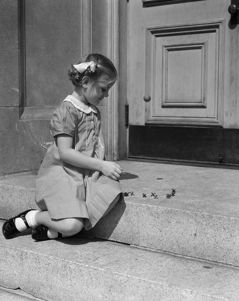 Detail of 1930s 1940s child little girl sitting on stoop playing jacks by Anonymous