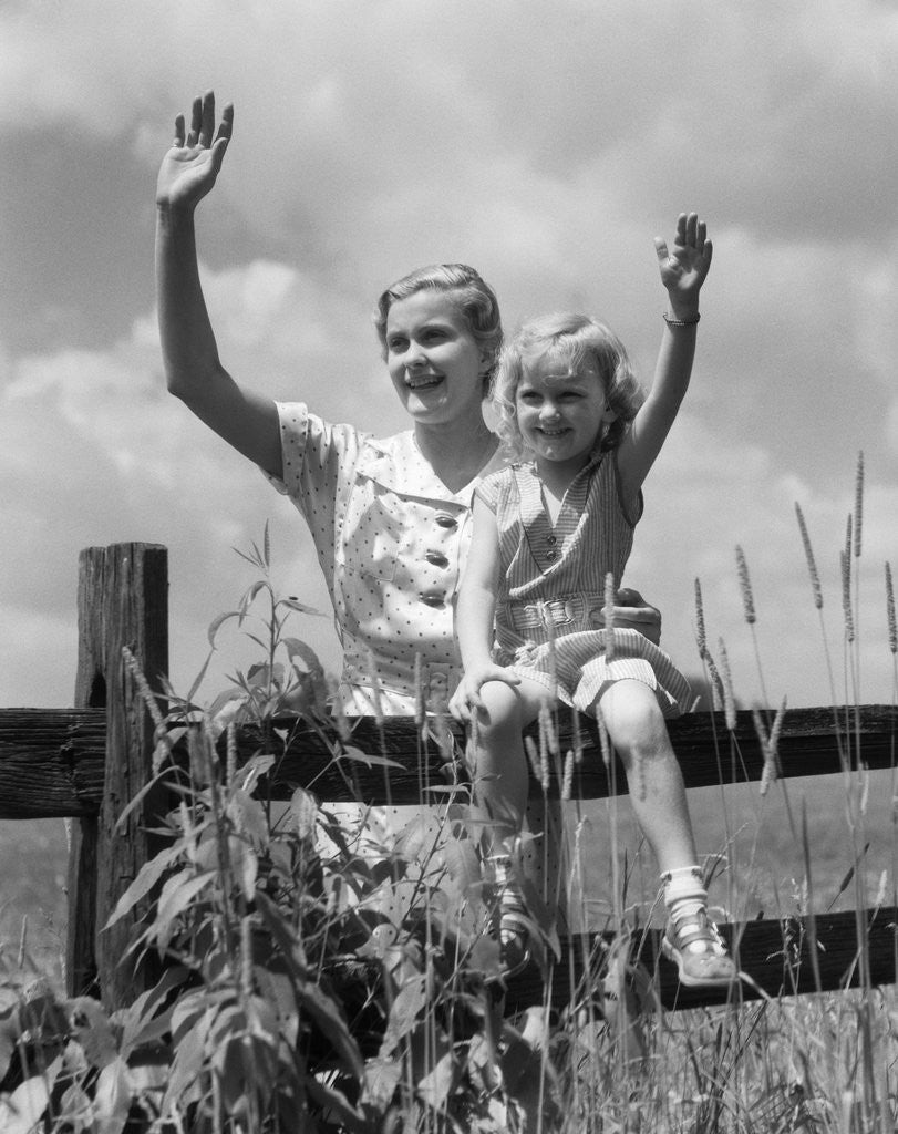 Detail of 1930s girl sitting on fence with woman next to her in field waving by Anonymous