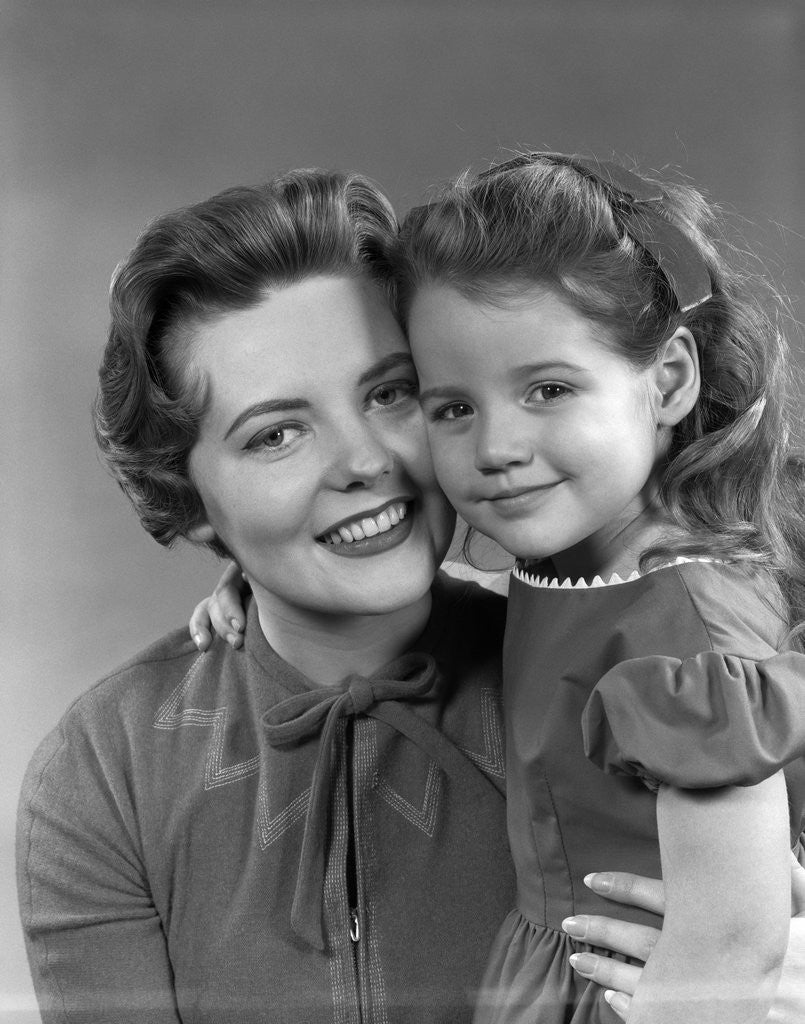 Detail of 1950s girl daughter smiling hugging woman mother cheek to cheek together by Anonymous