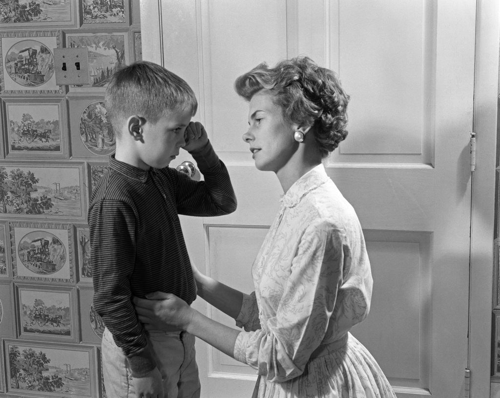 Detail of 1960s sad crying boy rubbing his eyes is comforted or disciplined by his caring mother by Corbis