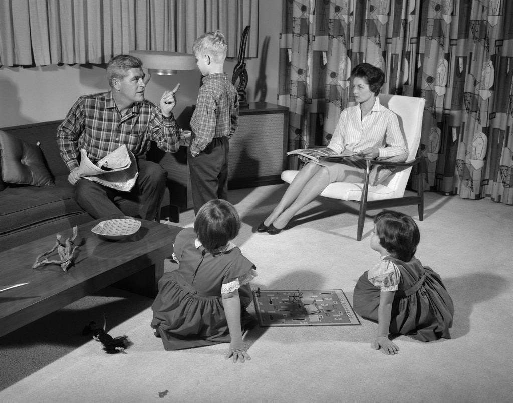 Detail of 1960s family of four in living room boy is being disciplined by dad shaking finger by Anonymous