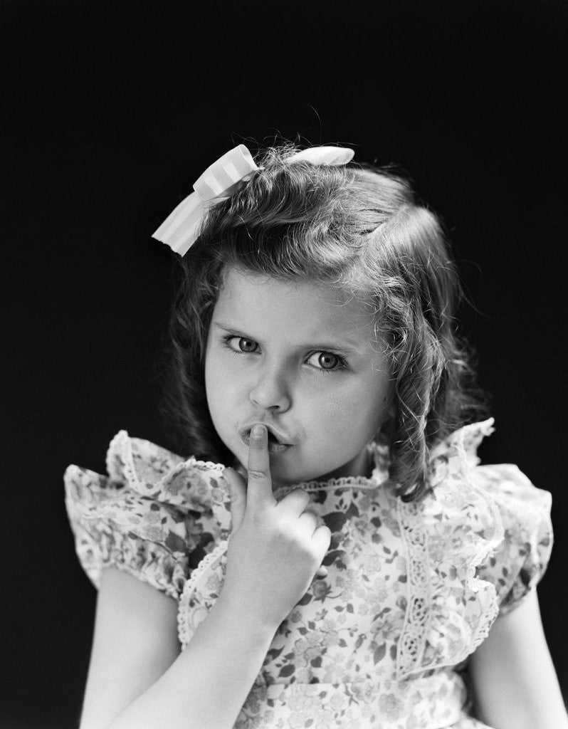 Detail of 1950s child serious little girl pressing finger to lips hush be quiet secret by Anonymous