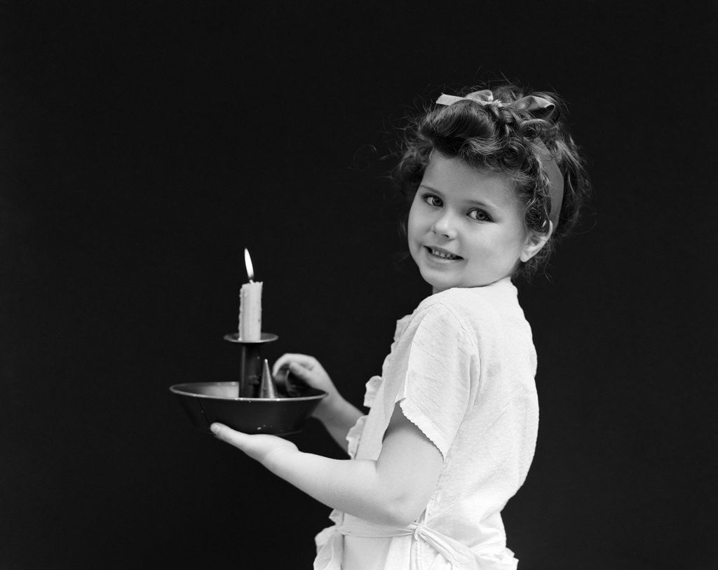 Detail of 1940s child little girl holding candle looking at camera by Anonymous