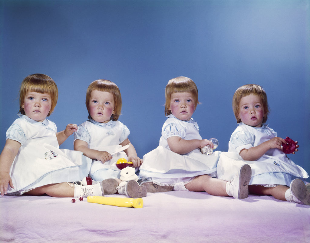 Detail of 1950s 1960s portrait of quadruplets 4 red haired girls wearing dresses sitting in a row by Corbis