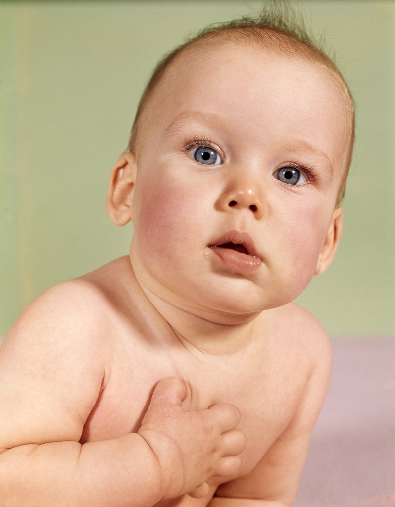 Detail of 1960s baby head portrait with sincere serious facial expression hand over heart gesture looking at camera by Anonymous
