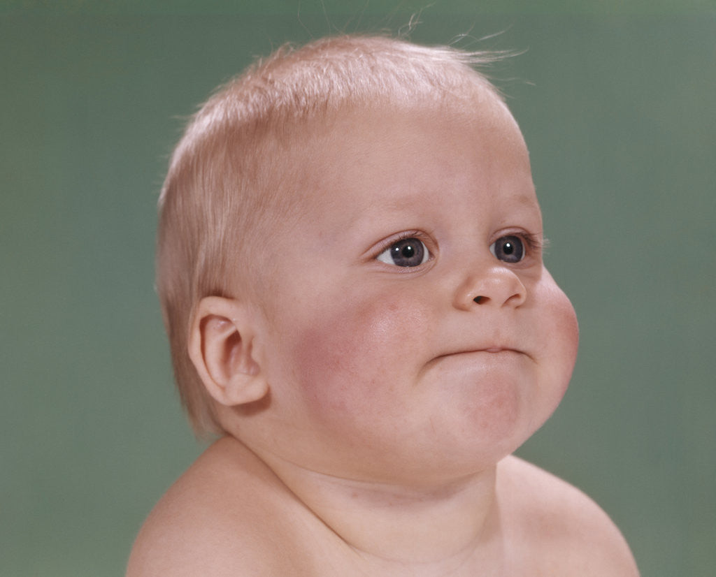 Detail of 1960s portrait of blond baby chubby cheeks with funny face expression by Corbis